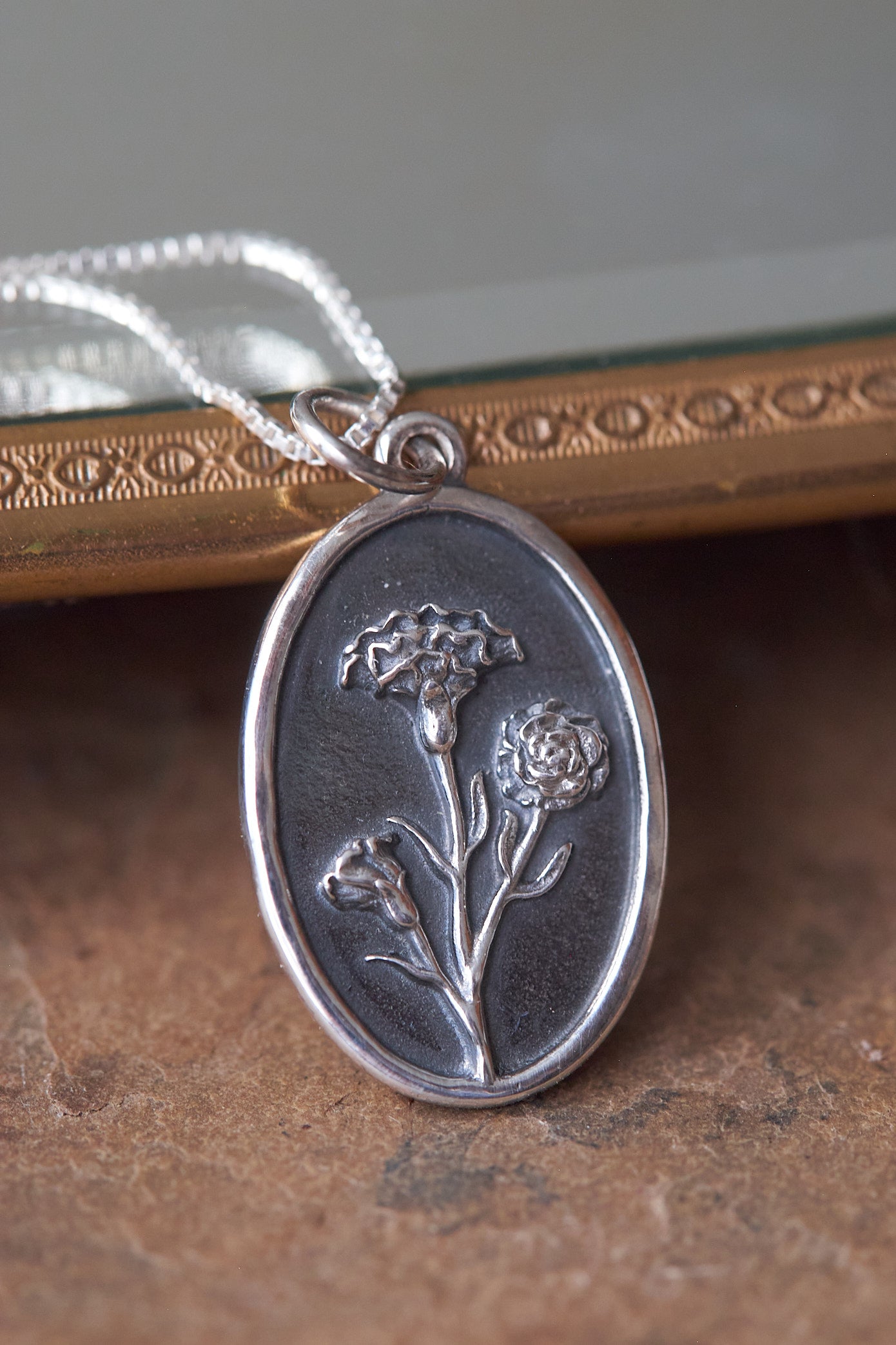 Silver pendant with floral design on a brown slate surface
