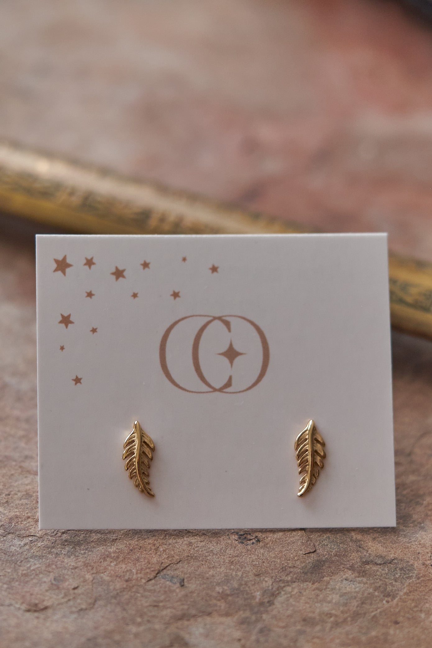 Gold leaf  earrings on a branded card with a blurred background