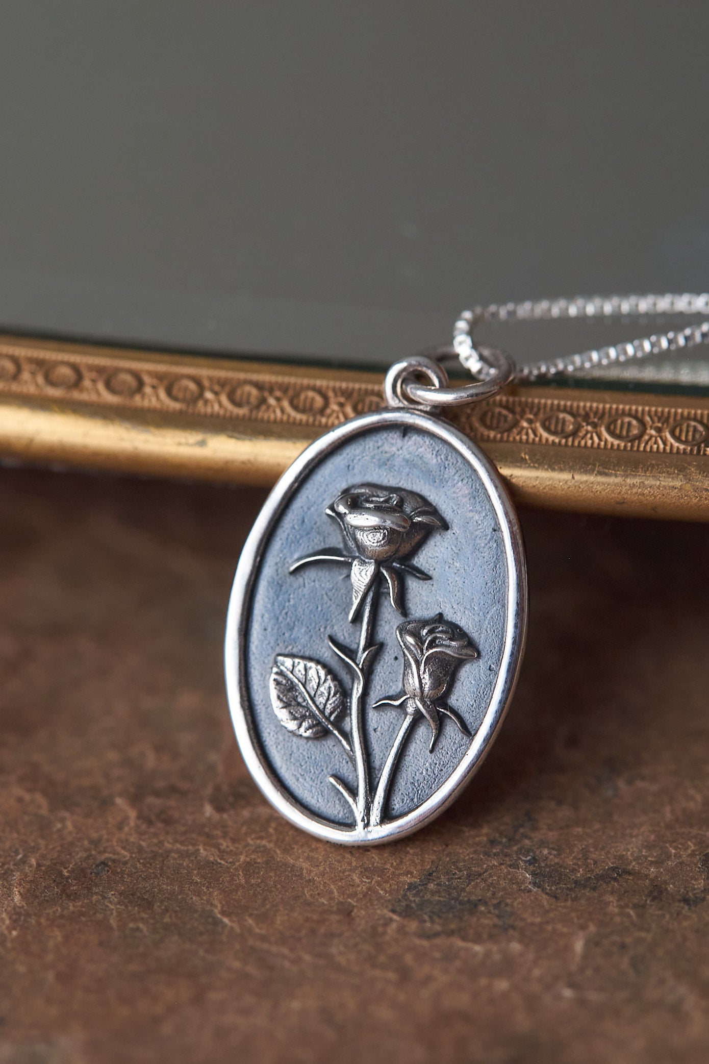 Silver pendant with rose design on a textured surface