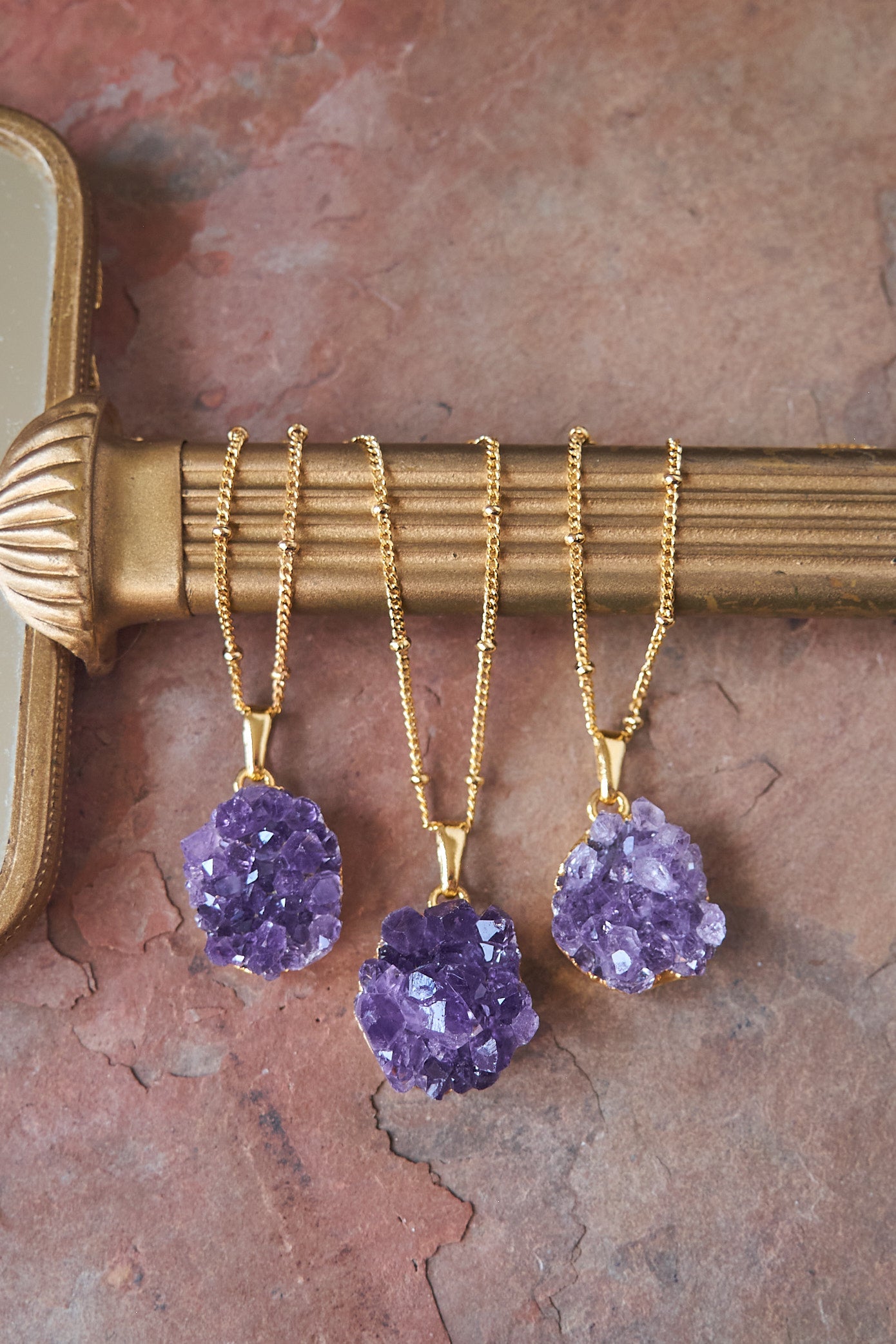 3 purple amethyst necklaces displayed on gold mirror