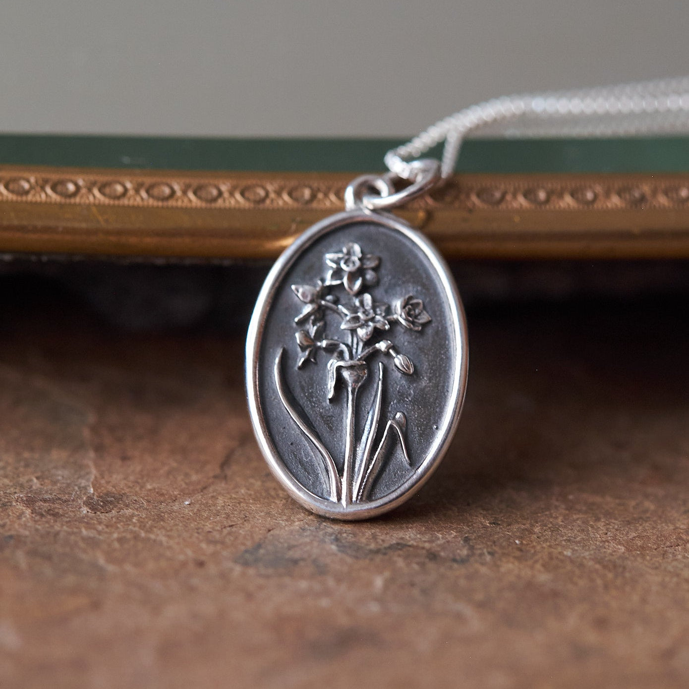 Silver pendant with narcissus design on a textured surface