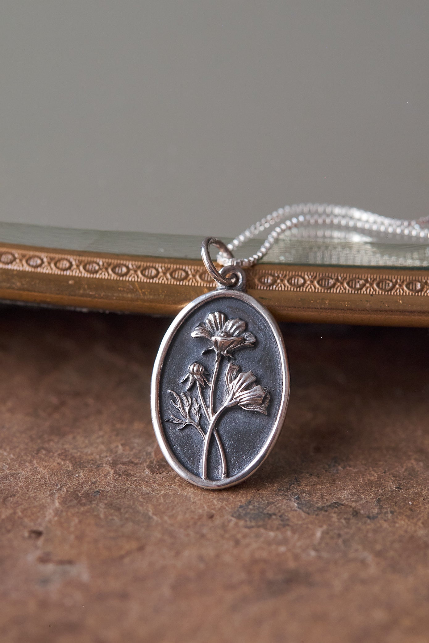 Silver pendant with floral design on a textured surface