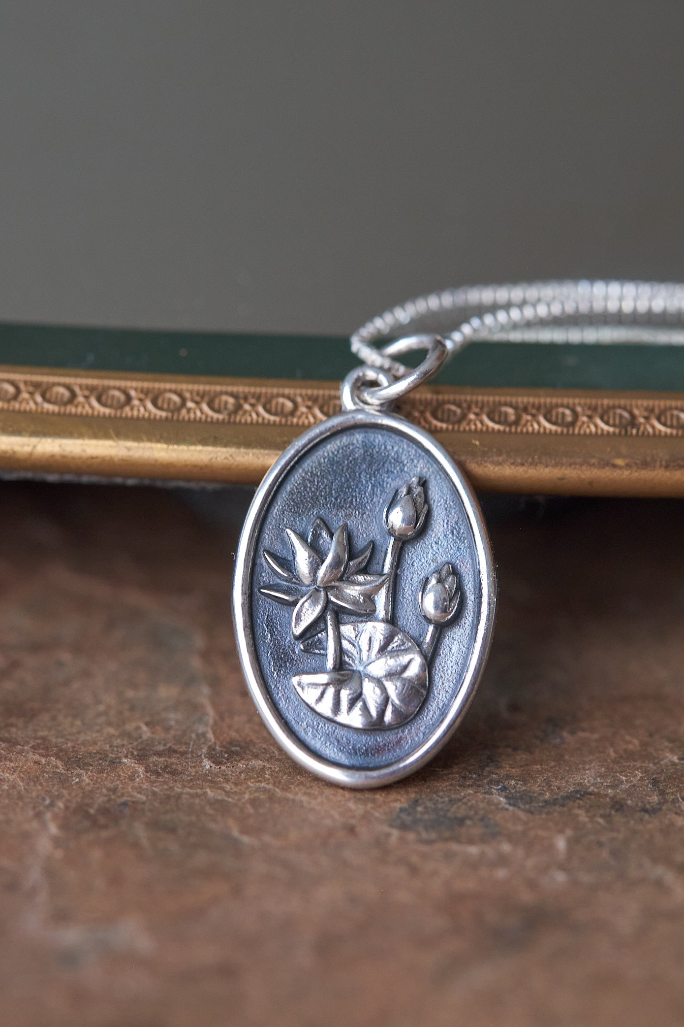 Silver pendant with waterlily design on a slate surface