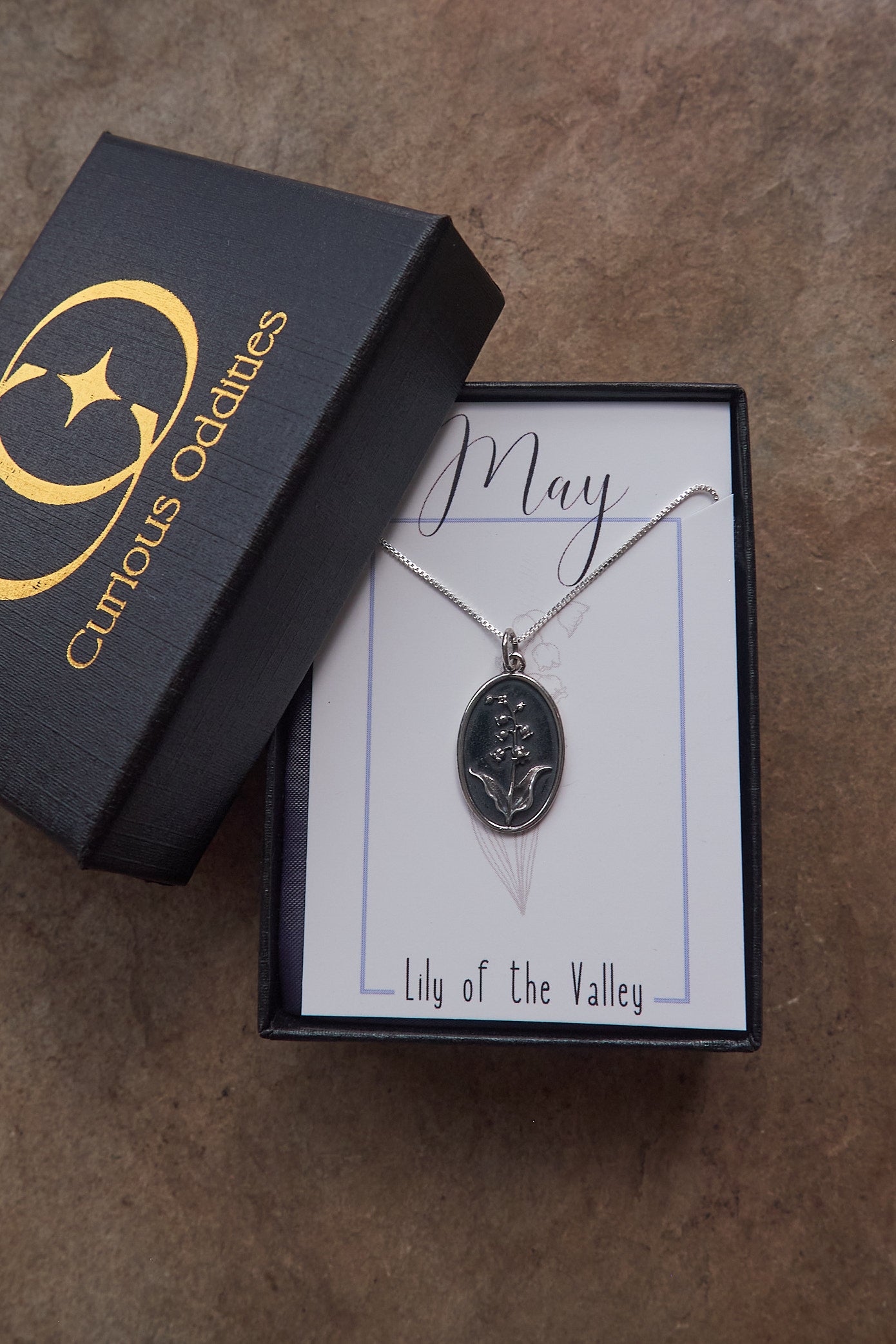 Jewelry box with a necklace featuring a 'Lily of the Valley' pendant on a brown surface