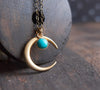 Matte gold half moon necklace with delicate turquoise accent displayed with dark brass chain