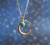 Matte gold half moon necklace with delicate turquoise accent with blurry celestial background 