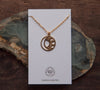 Round, matte gold moon and sun circle necklace on Curious Oddities white backing card