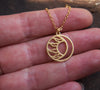 Round, matte gold moon and sun circle necklace in hand